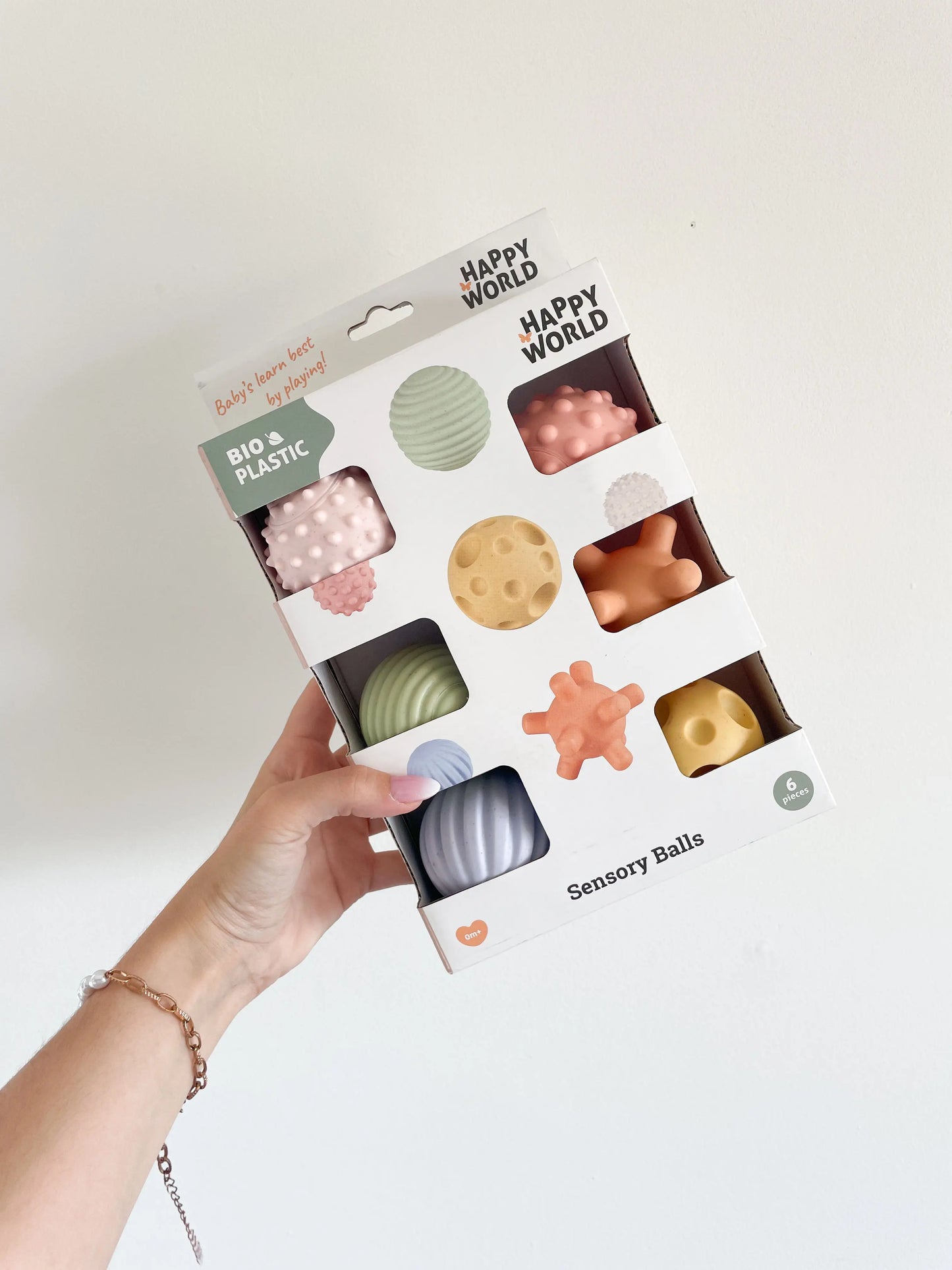 Boîte de 6 balles sensorielles bébé tenue à la main sur fond blanc – présentation du packaging