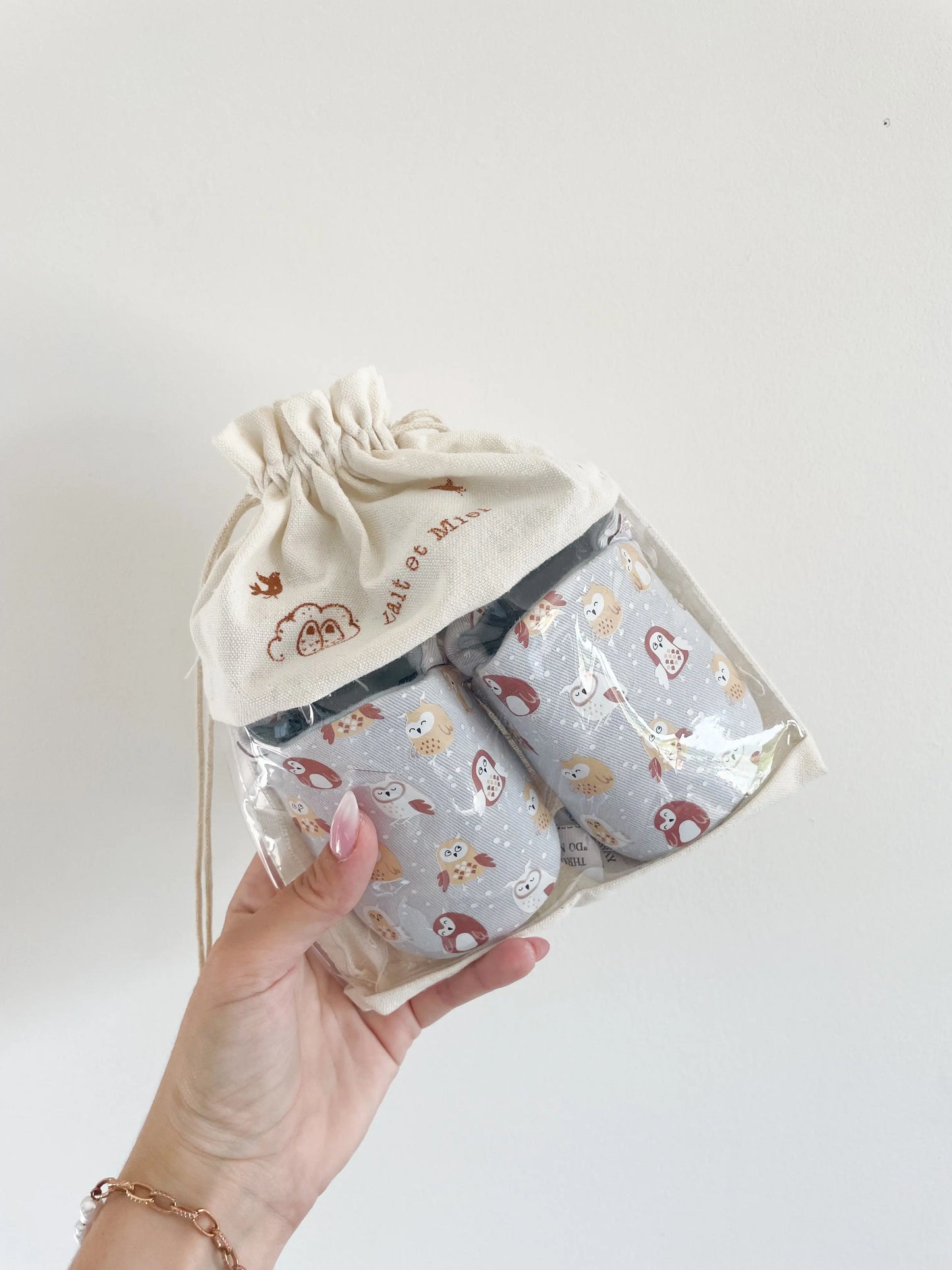 Chaussons bébé hibou souples, présentés dans un sachet en toile de jute lait et miel
