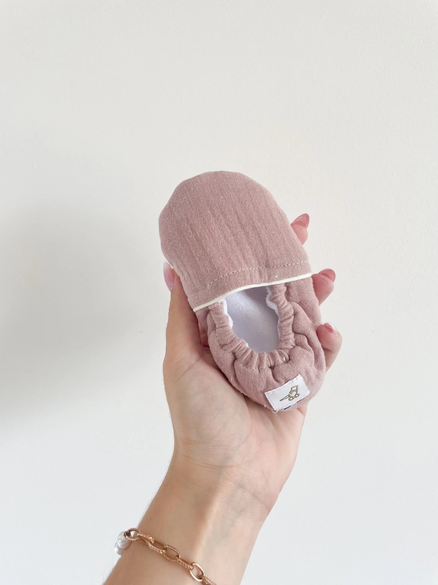 Chaussons souples vieux rose pour bébé, posés de face, matière douce et tour de cheville élastiqué