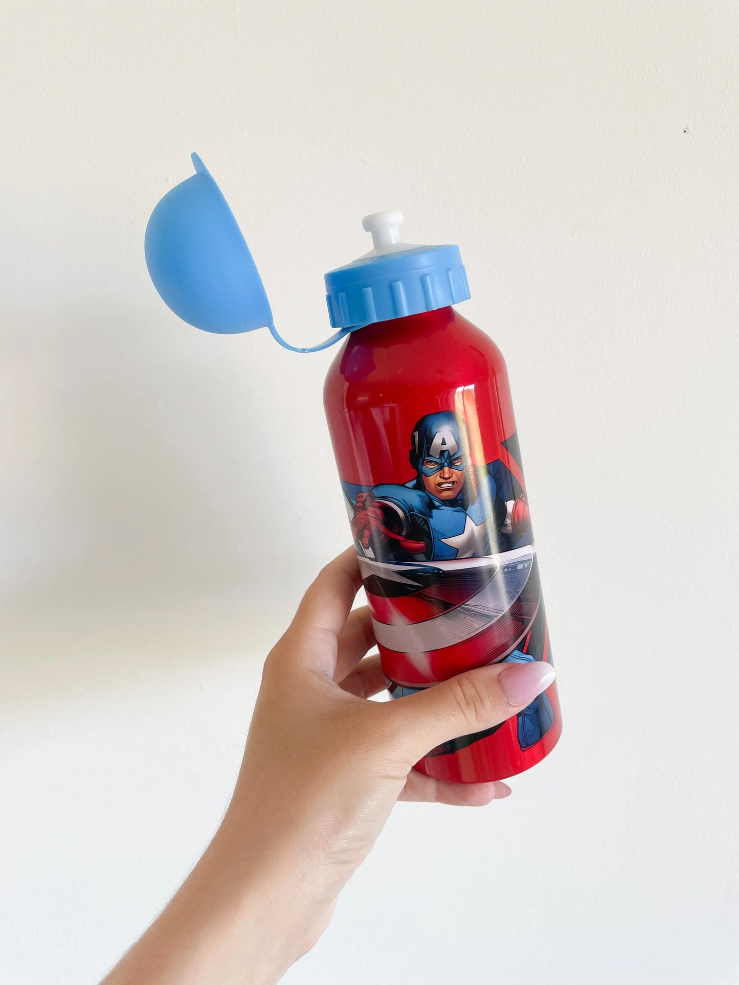 Gourde avengers - Captain America avec bouchon bleu ouvert, gourde prise dans une main sur fond blanc