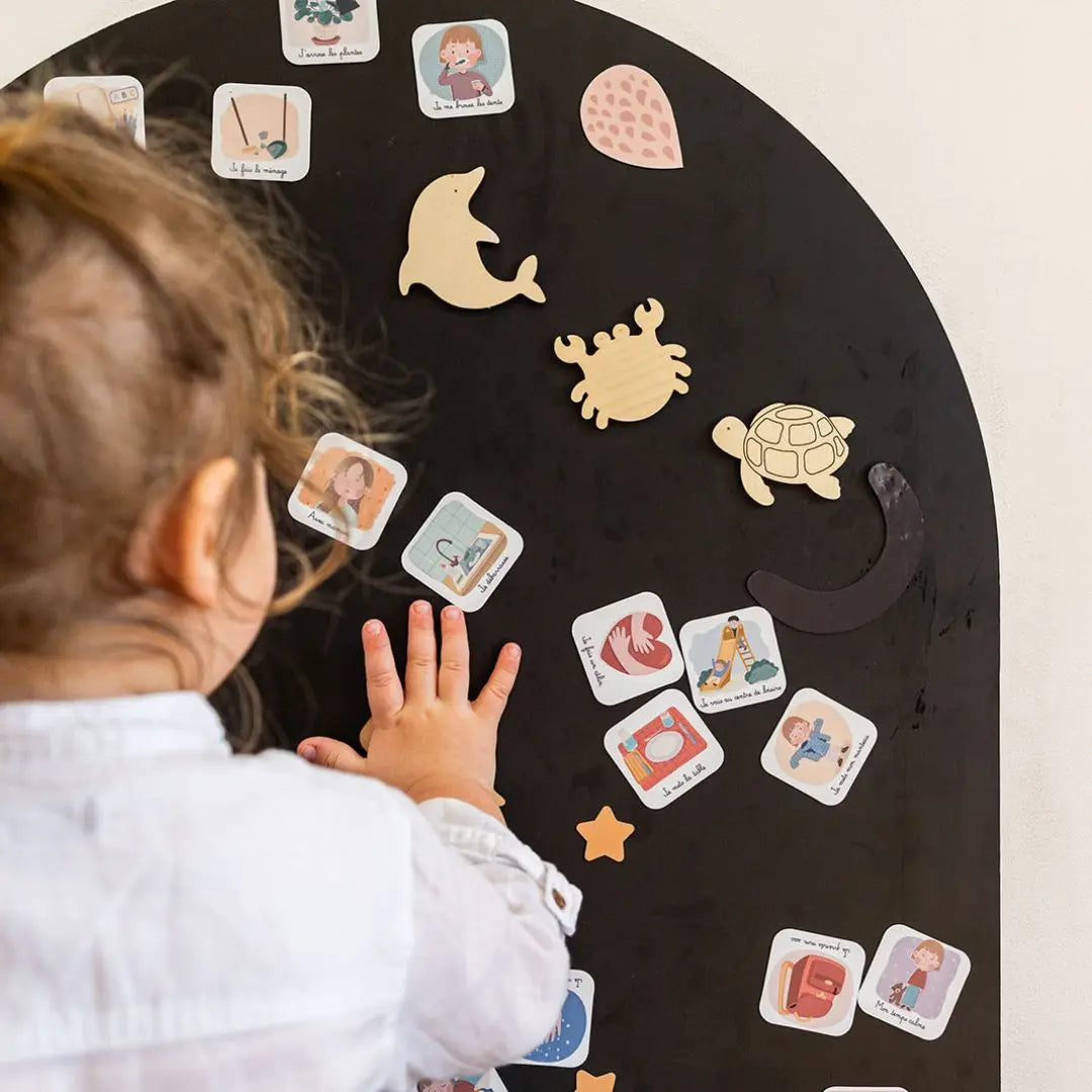 Enfant utilisant les magnets sur un tableau pour suivre sa routine quotidienne