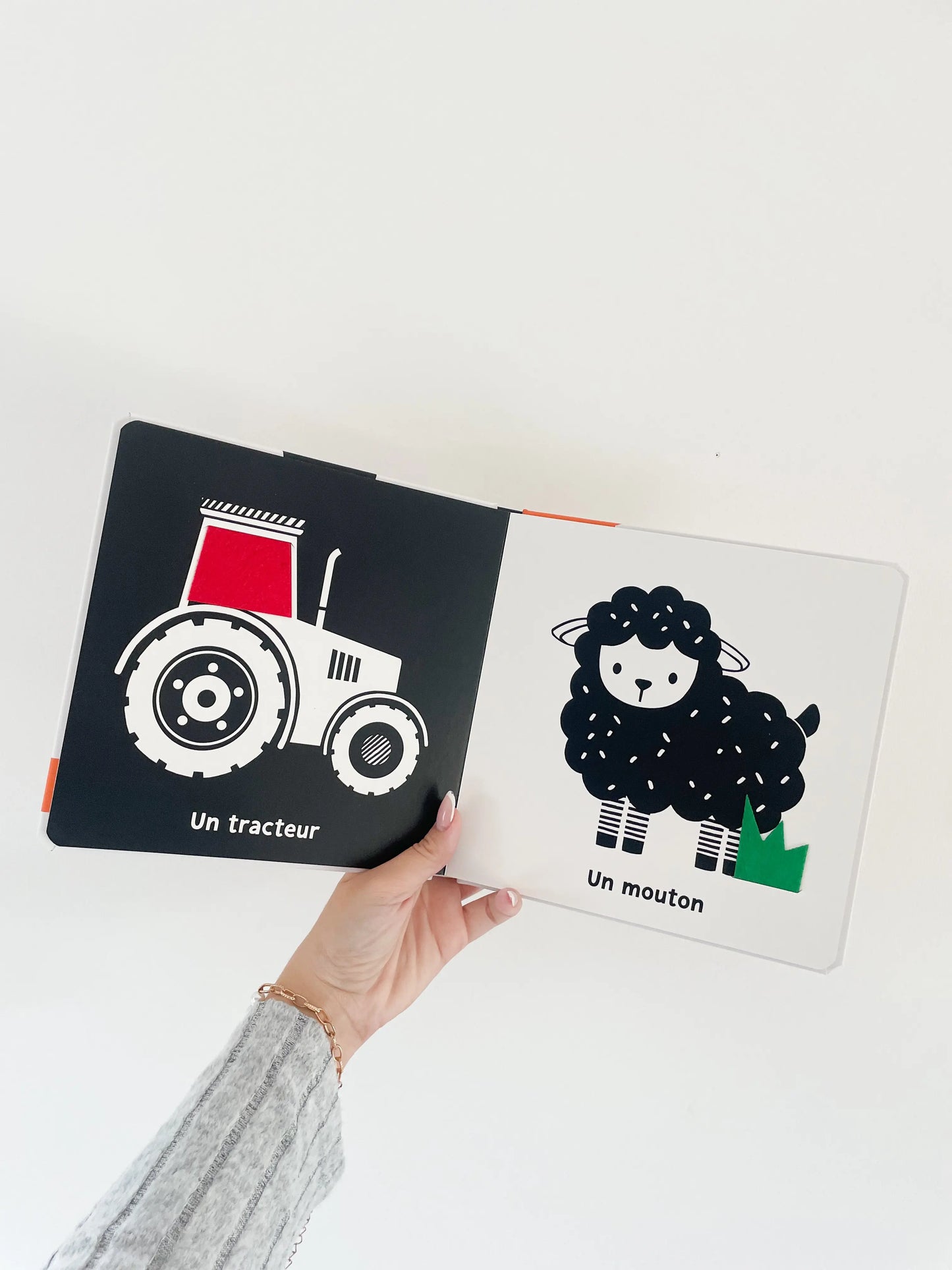 Livre noir et blanc pour bébé sur la ferme Mes premiers flaps. Page intérieur du livre avec un tracteur et un mouton