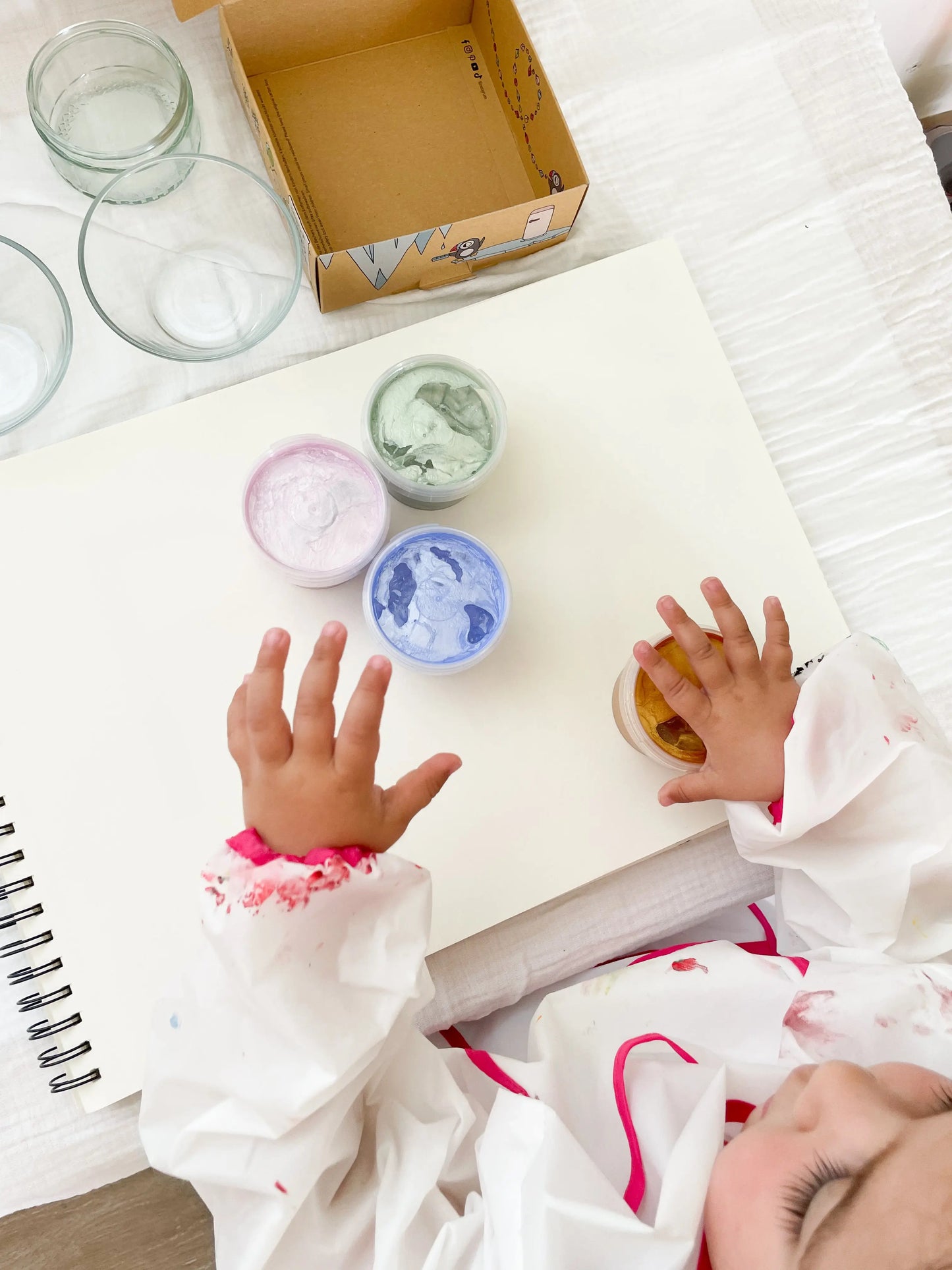 Activité créative : enfant avec de peinture a doigts sur une feuille blanche