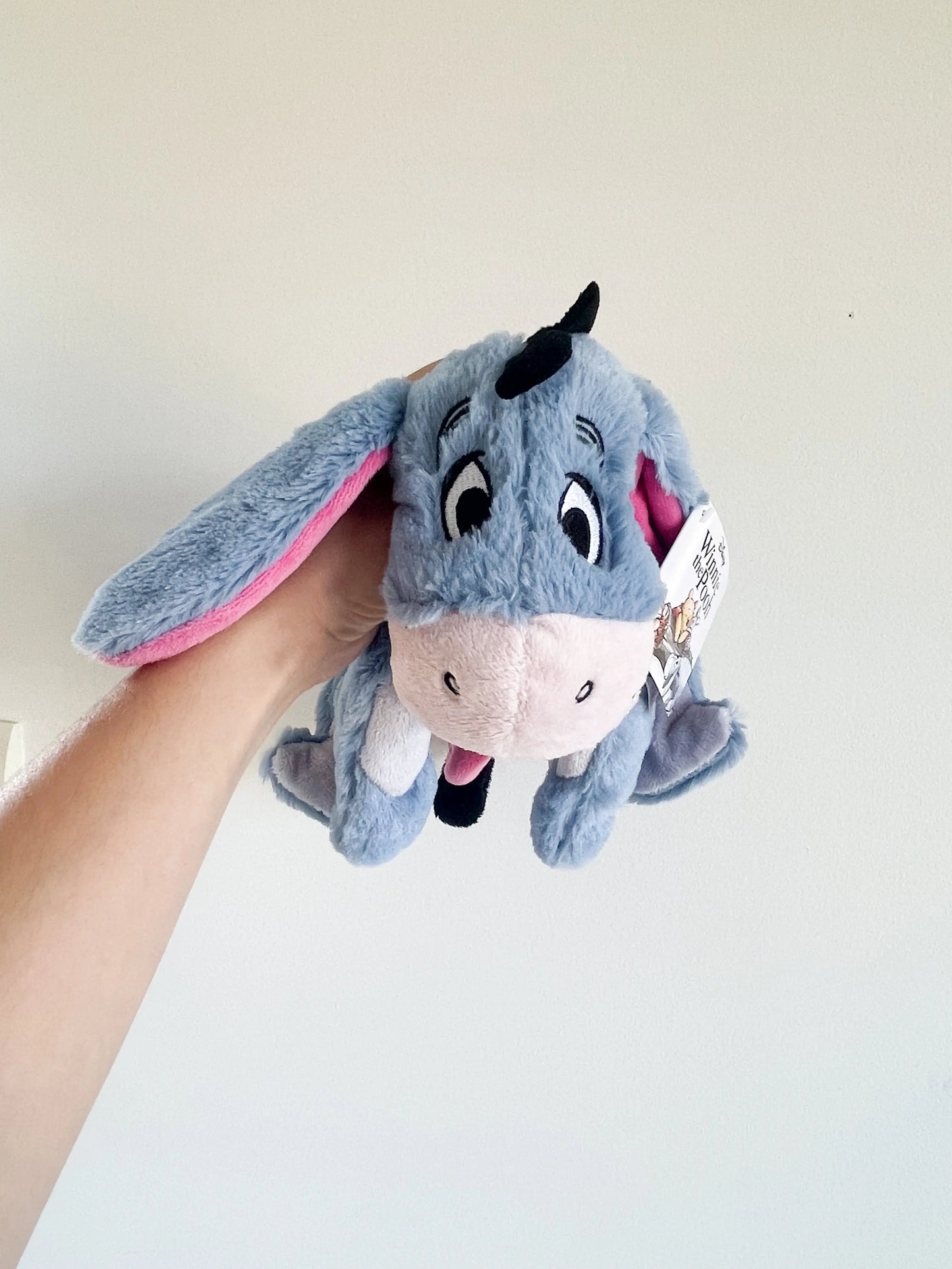 Peluche Bourriquet disney 25 cm tenue en main sur un fond blanc uni