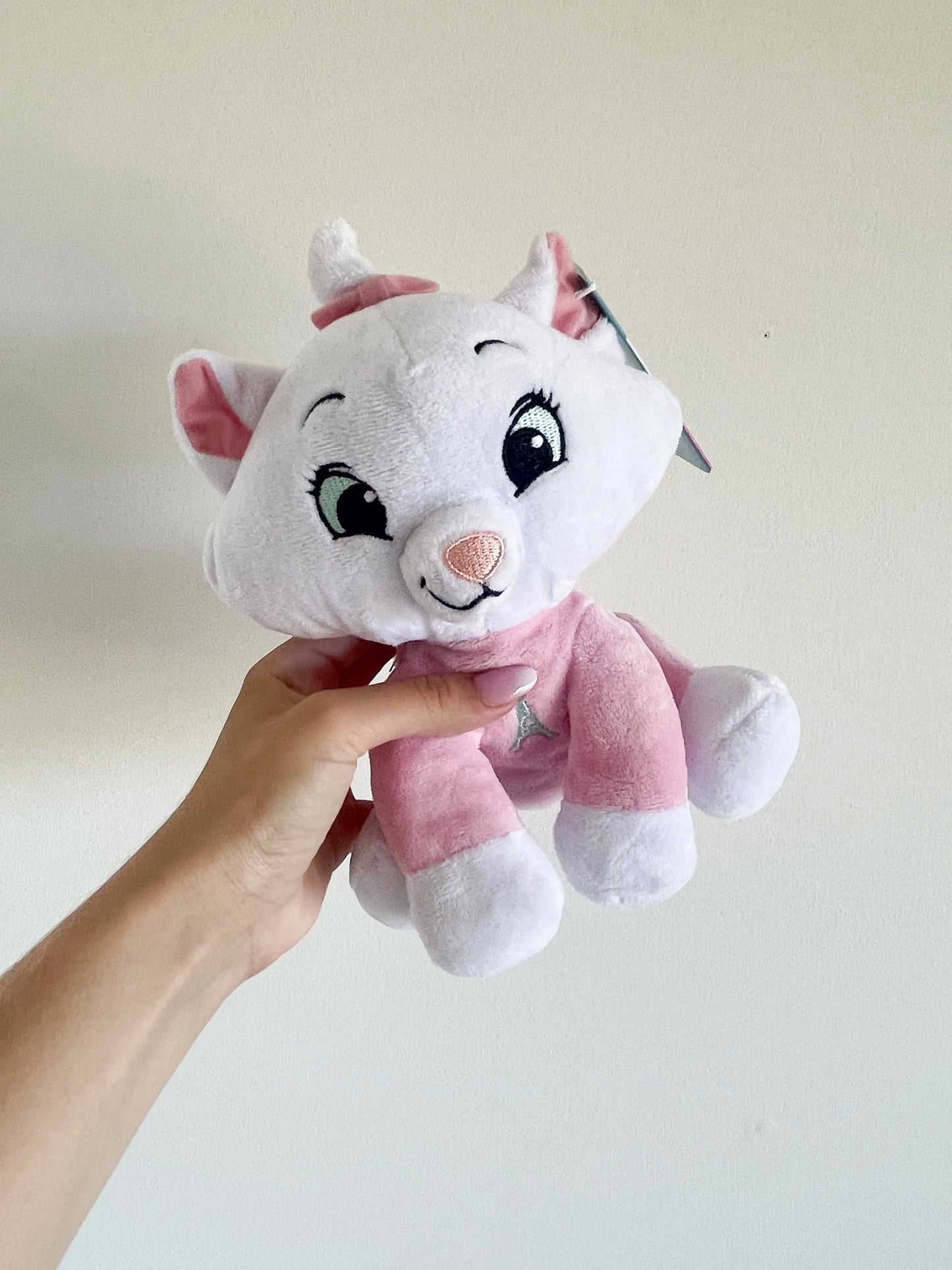 Peluche Marie des Aristochats 25 cm tenue par une main sur un fond blanc – vue de face