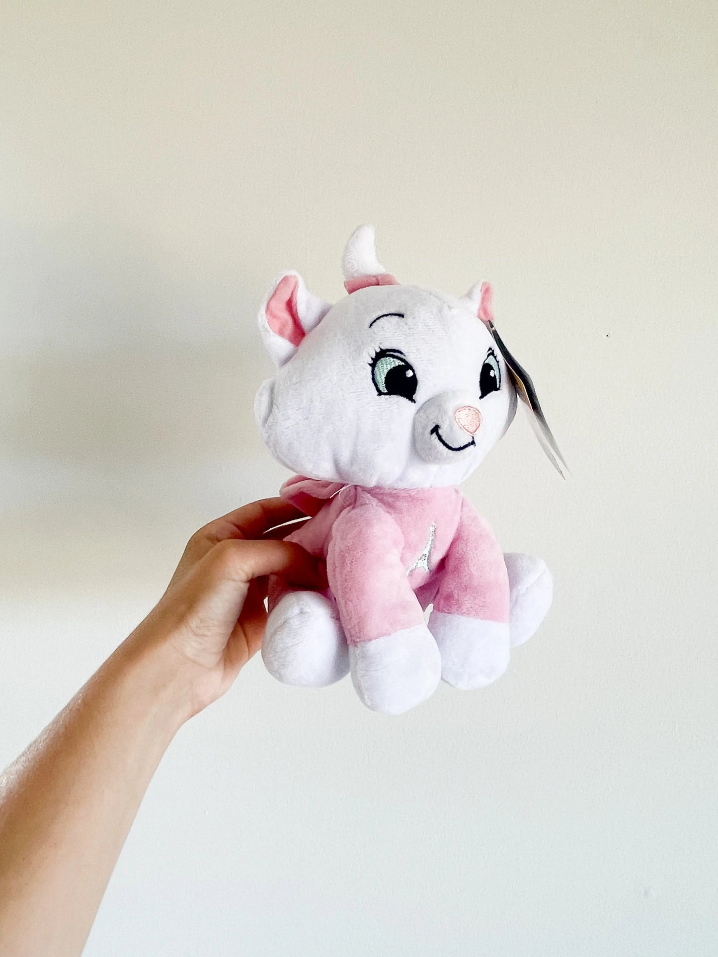 Peluche Marie tenu à la main – personnage Disney, expression souriante