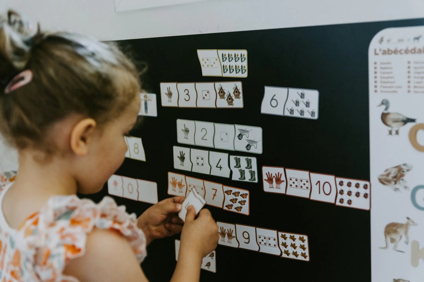 Enfant manipulant les pièces du puzzle magnétique sur un tableau