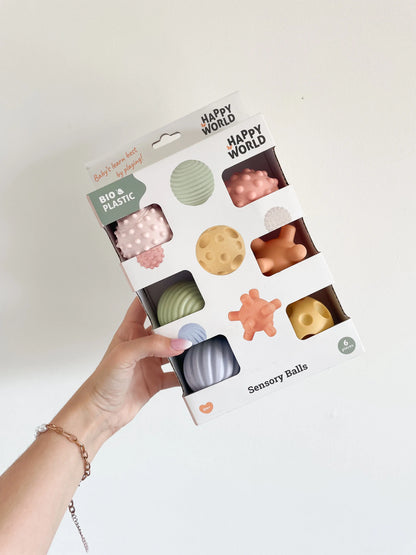 Boîte de 6 balles sensorielles bébé tenue à la main sur fond blanc – présentation du packaging

