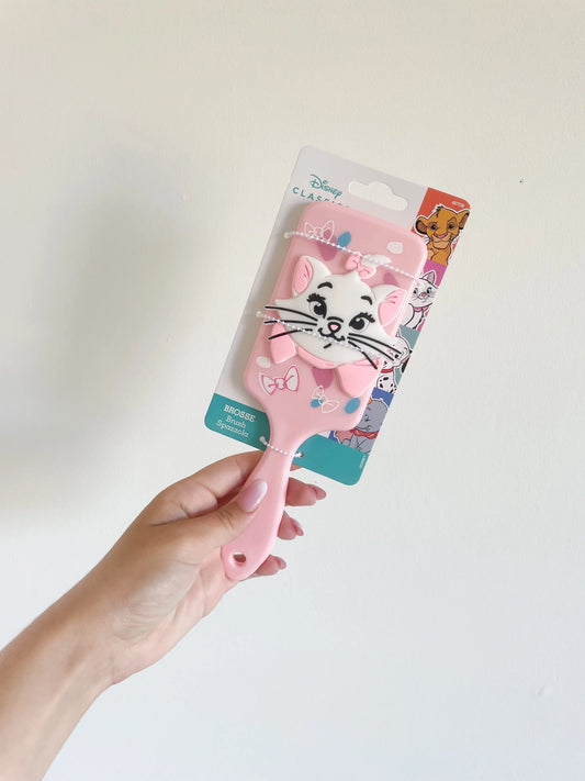 Brosse à cheveux Marie des Aristochats  pour enfant couleur rose. Marie en 3d silicone. Brosse a cheveux pour enfant pris dans la main sur fond blanc
