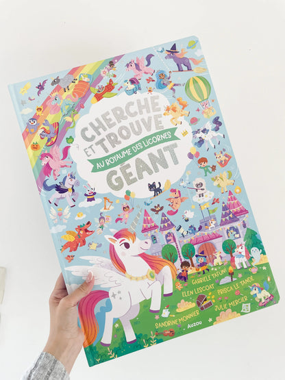 livre pour enfant Cherche et trouve geant- Au royaume des licornes. Livre de couverture licorne. Livre dans une main sur fond blanc