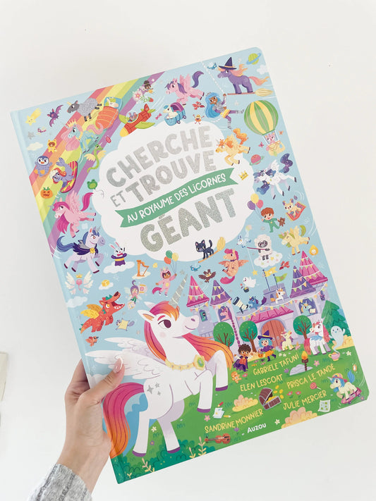 livre pour enfant Cherche et trouve geant- Au royaume des licornes. Livre de couverture licorne. Livre dans une main sur fond blanc