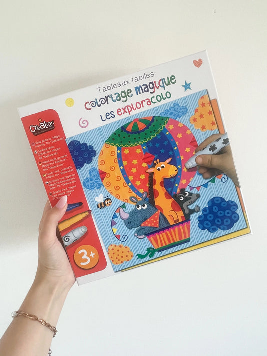 Le coloriage magique Les Exploracolo, tenu à la main sur fond blanc, conçu pour enfants dès 3 ans.