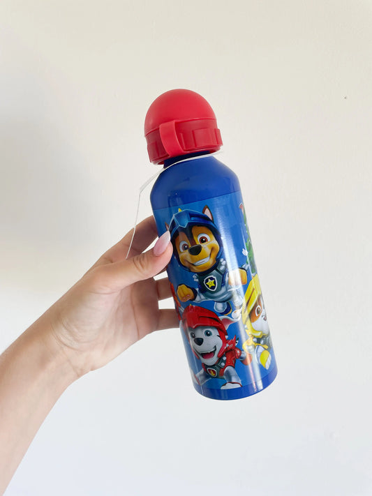 Gourde Pat patrouille pour enfant bleu et rouge avec 3 personnages, pris dans une main sur fond blanc