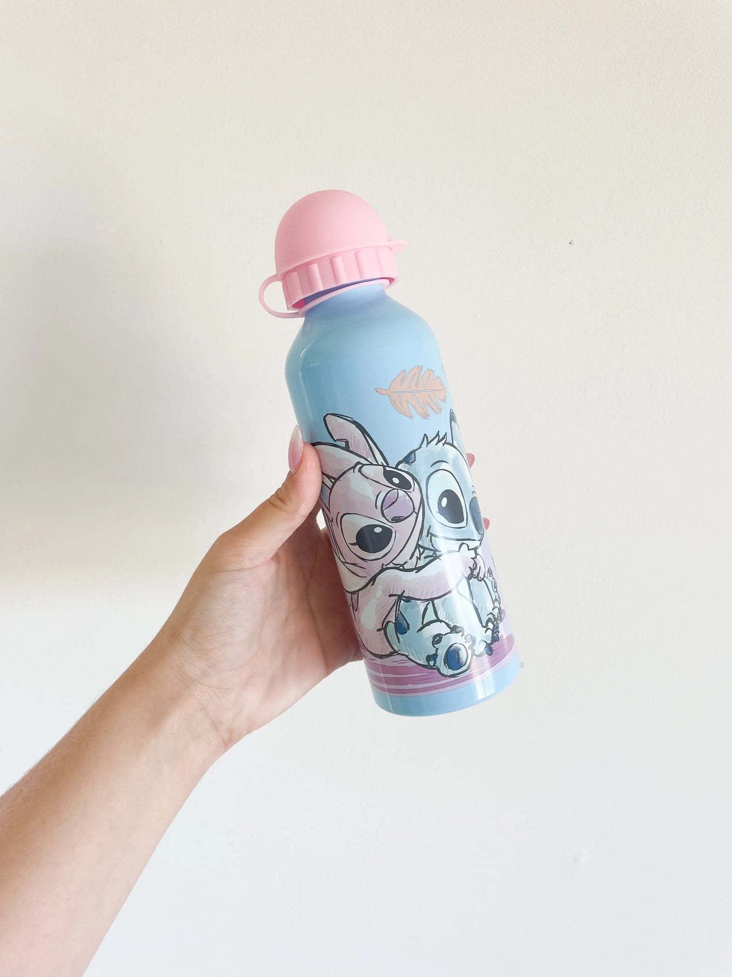 Gourde enfant Stitch et Angel bleu et rose tenue à la main sur fond blanc