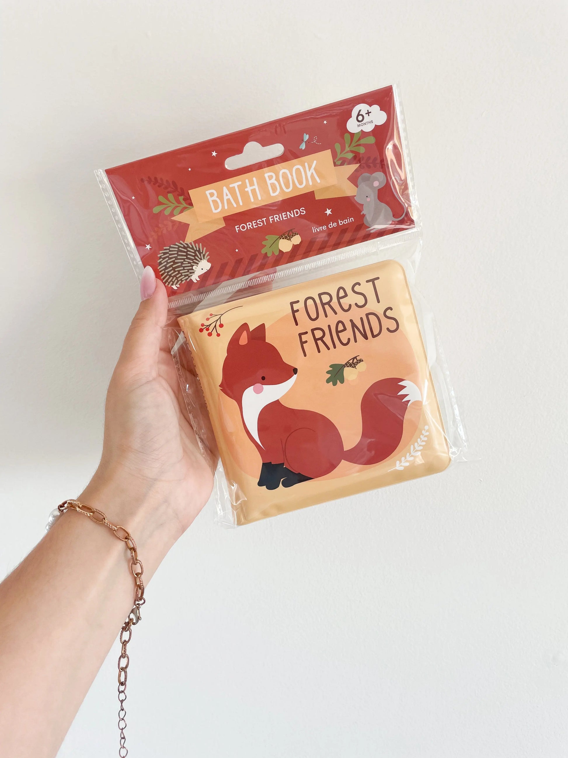 Livre de bain “Amis de la forêt” tenu à la main sur fond blanc – couverture rouge avec animaux