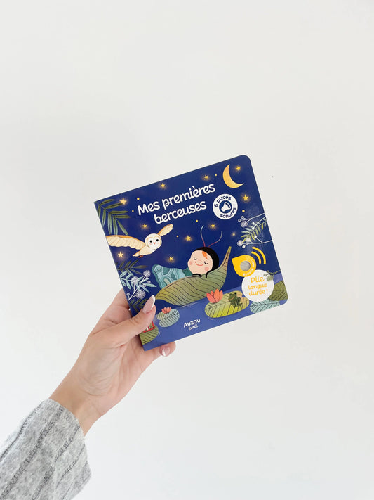Livre sonore - Mes premières berceuses pour bébé dès 1 an. Livre de couverture bleu. Livre dans une main sur fond blanc