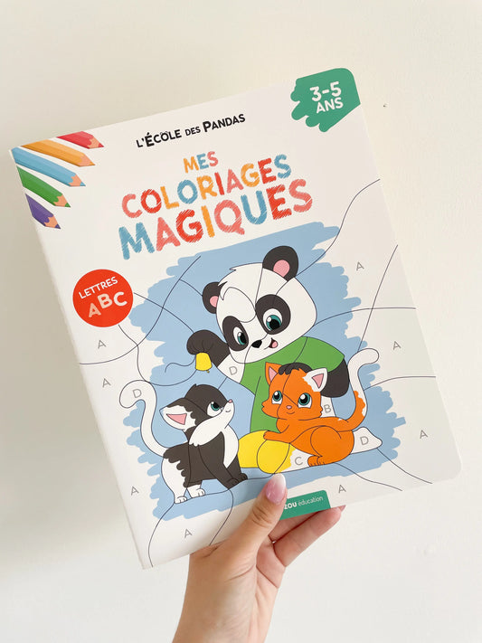 Coloriages magiques sur les lettres thème panda pour les 3-5 ans. Page de couverture. L'école des panda. Livre dans une main sur un fond blanc.