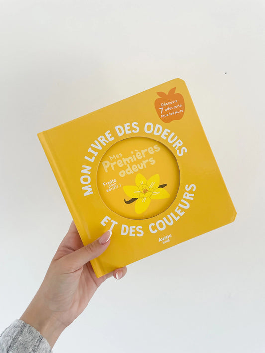 Mon livre des odeurs et des couleurs - Mes premières odeurs. Couverture du livre jaune. Livre imagier et odeurs dès 1an. Livre dans une main sur fond blanc.