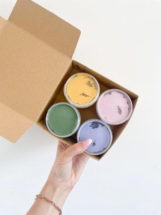 Vue du coffret peinture au doigt bio vegan Luka avec 4 pots colorés dans une boîte kraft prise a la main sur fond blanc