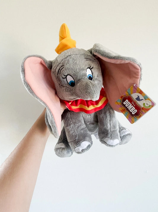 Peluche disney Dumbo 30cm avec de grandes oreilles, tenu a la main sur fond blanc