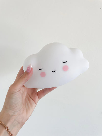 Veilleuse bébé nuage blanche avec visage souriant endormi, veilleuse tenue a la main sur un fond blanc