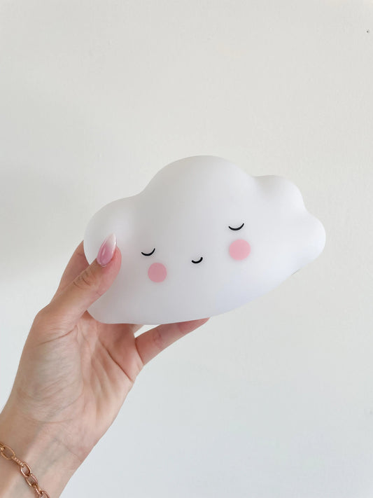 Veilleuse bébé nuage blanche avec visage souriant endormi, veilleuse tenue a la main sur un fond blanc