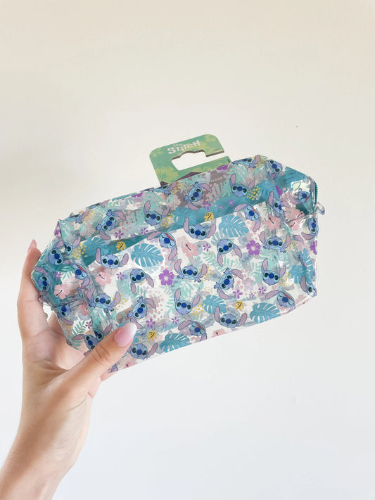 Trousse de toilette Stitch disney transparente et bleu avec pleins de petit stitch. Trousse de beauté enfant pris dans une main sur fond blanc